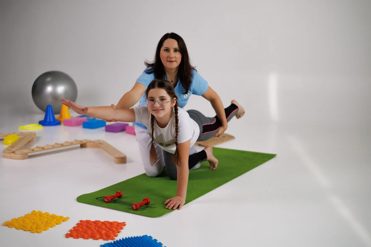 Фізична терапевтка з дівчинкою пацієнткою на занятті