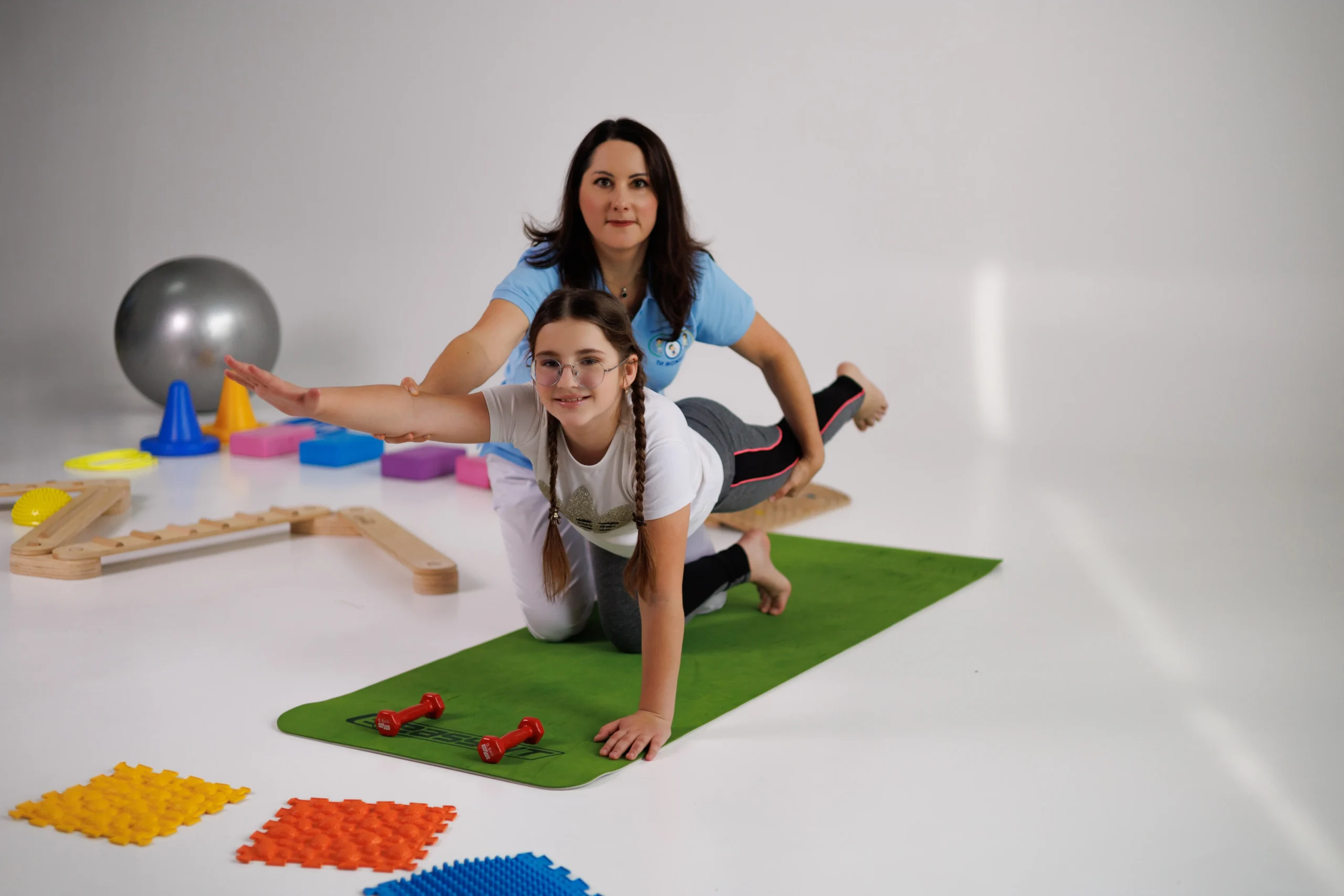 Фізична терапевтка з дівчинкою пацієнткою на занятті